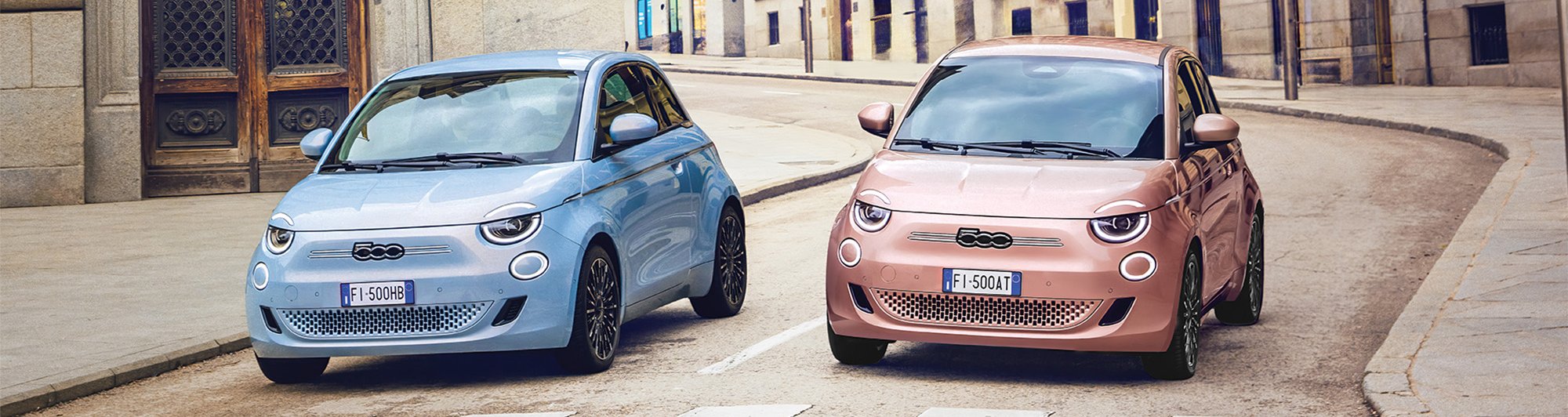 Two small cars, one blue and one pink, parked side by side on a city street.