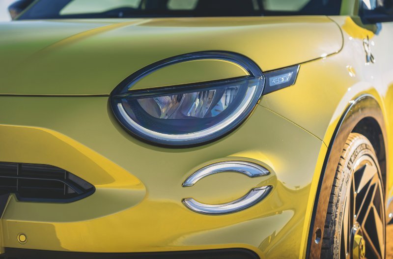Close-up of a yellow car's headlight and front wheel.