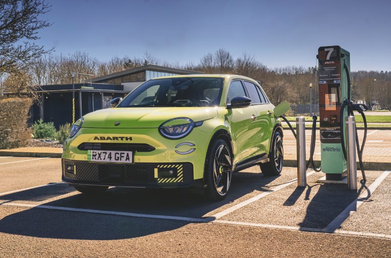 Bright green car charging at an electric vehicle station in a car park.