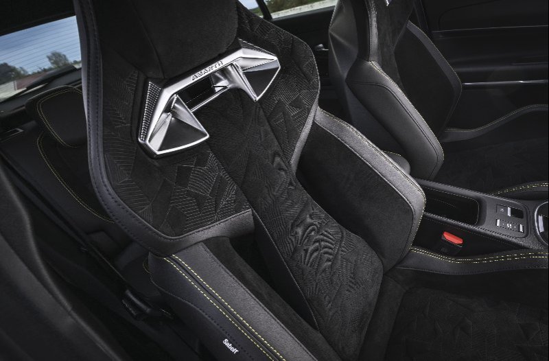 Close-up of a car's sports seat with intricate pattern and yellow stitching.