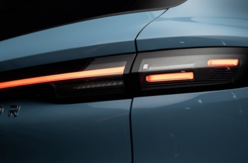 Close-up of a blue car's rear light with red illuminated strips.