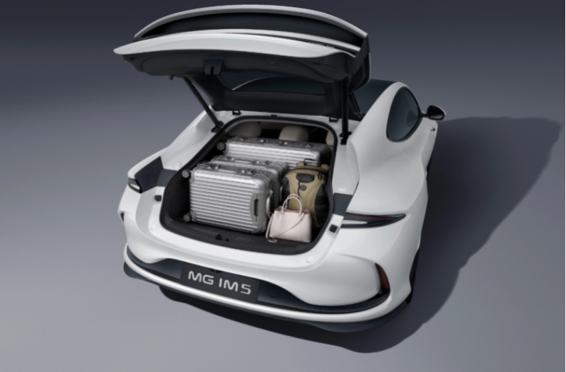 Open boot of white MG IM5 car loaded with suitcases and bags.