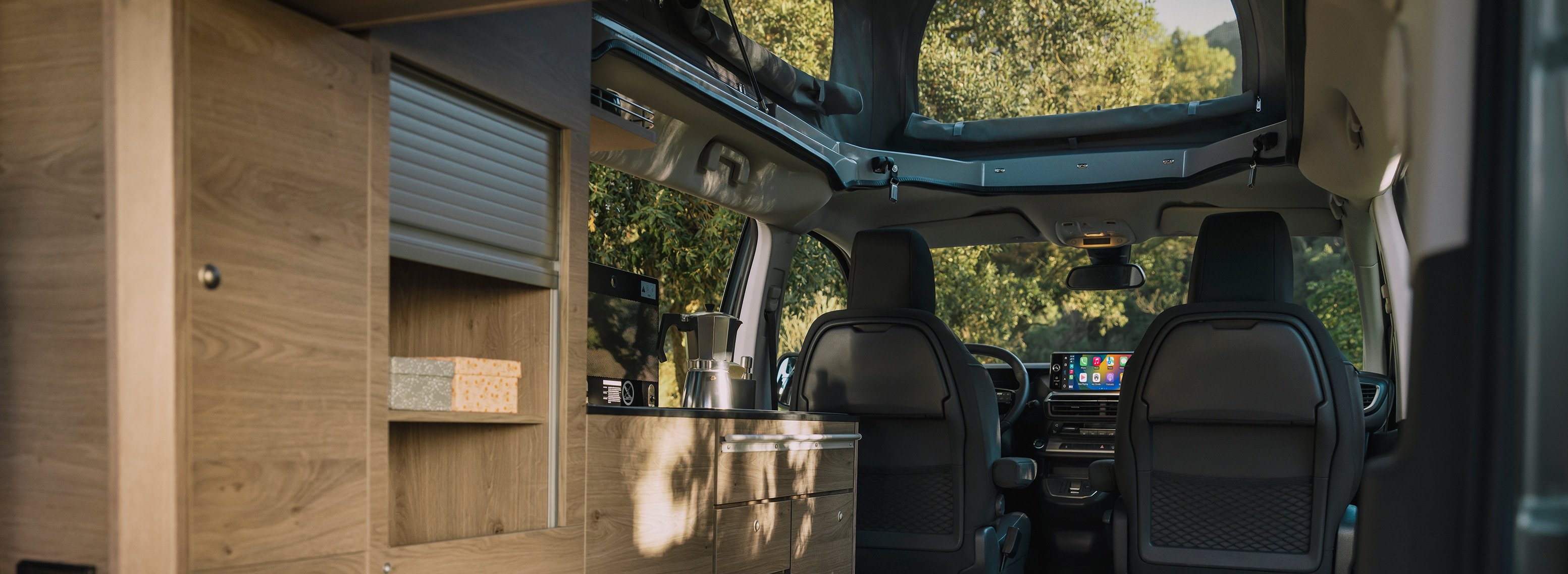 Interior of a campervan with wooden fittings and two front seats visible.