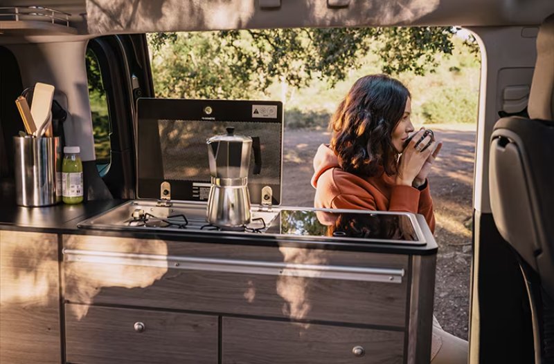Woman drinking coffee outside the Citroen Holidays