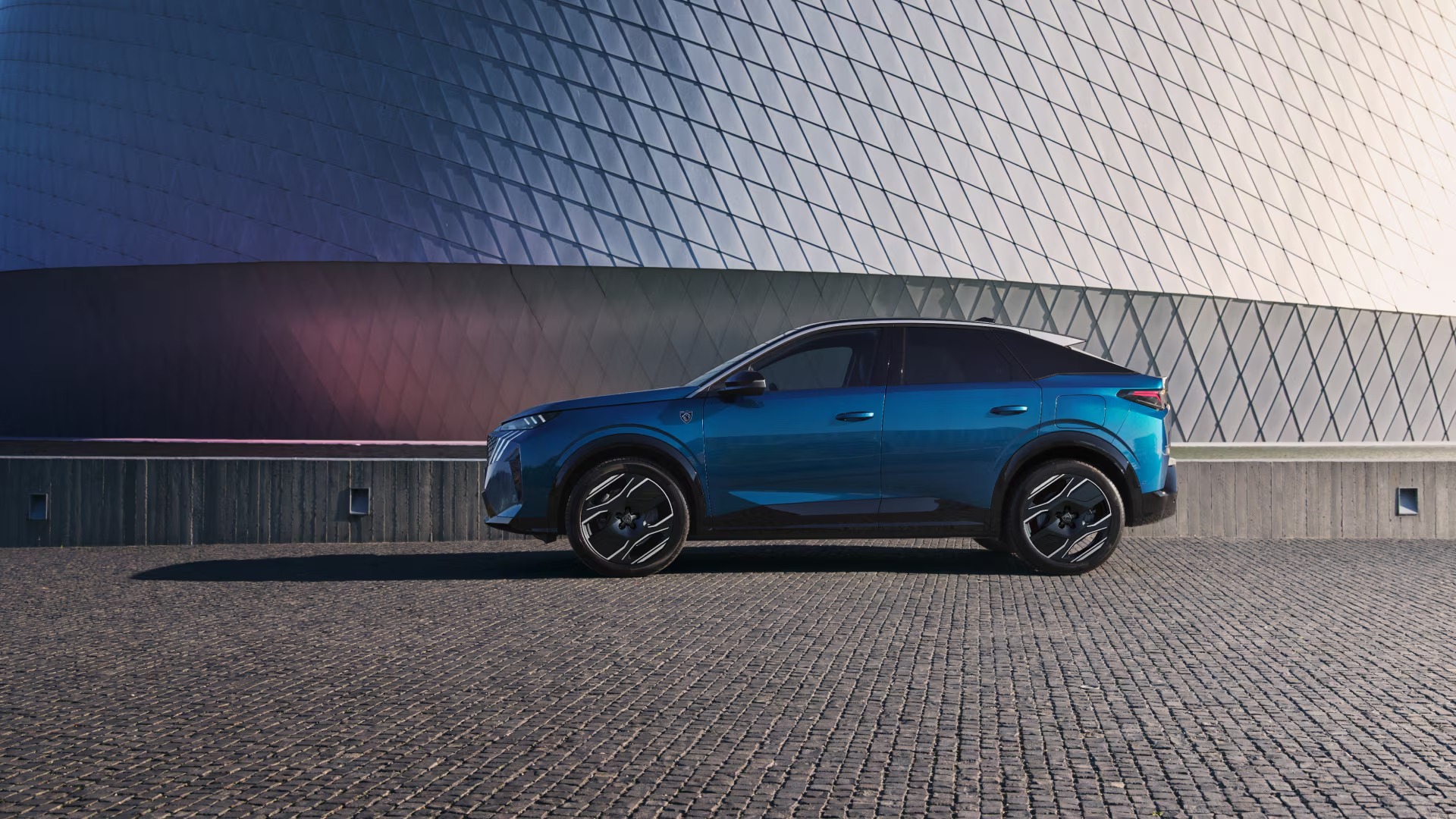 Side view of a blue SUV parked on a cobblestone surface.