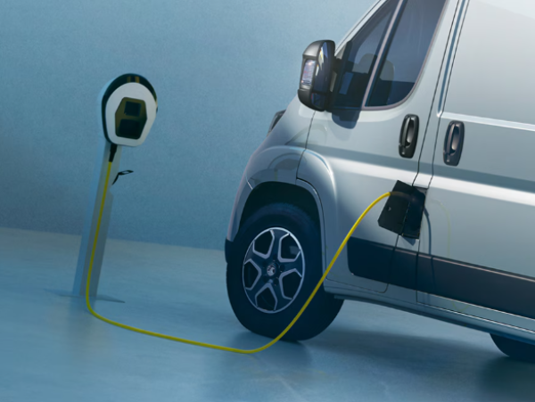 Electric van plugged into a charging station with a yellow cable.