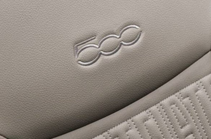 Close-up of car seat with 500 logo embossed on grey upholstery.