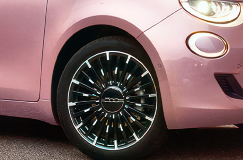 Close-up of a pink car's front wheel with a black and silver alloy design.