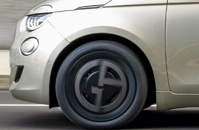 Close-up of a silver car's front section driving on a road.