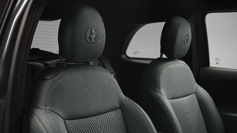 Front seats of a car with textured upholstery and logo on headrests.