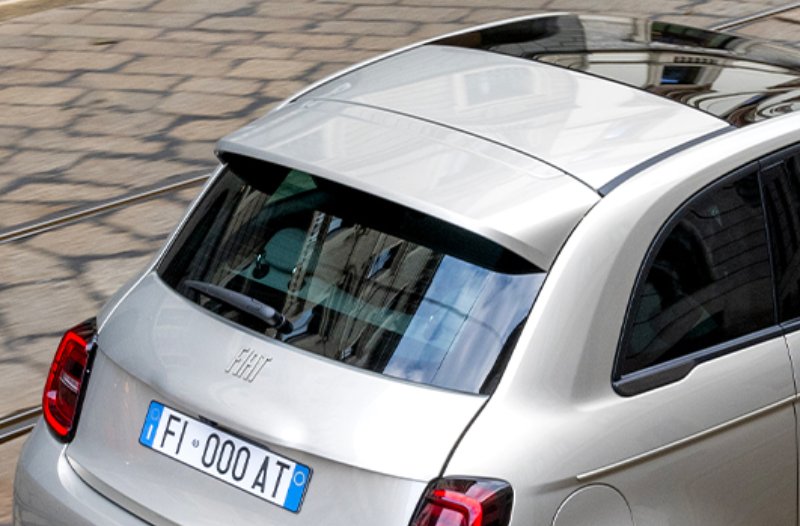 Silver car on cobblestone street, viewed from the rear-left.