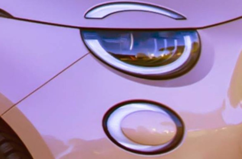 Close-up of a car's front light and logo in a pink hue.