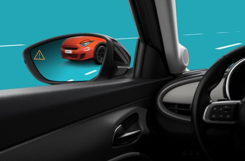 Car's side mirror showing a red car in the lane with a yellow warning symbol visible.