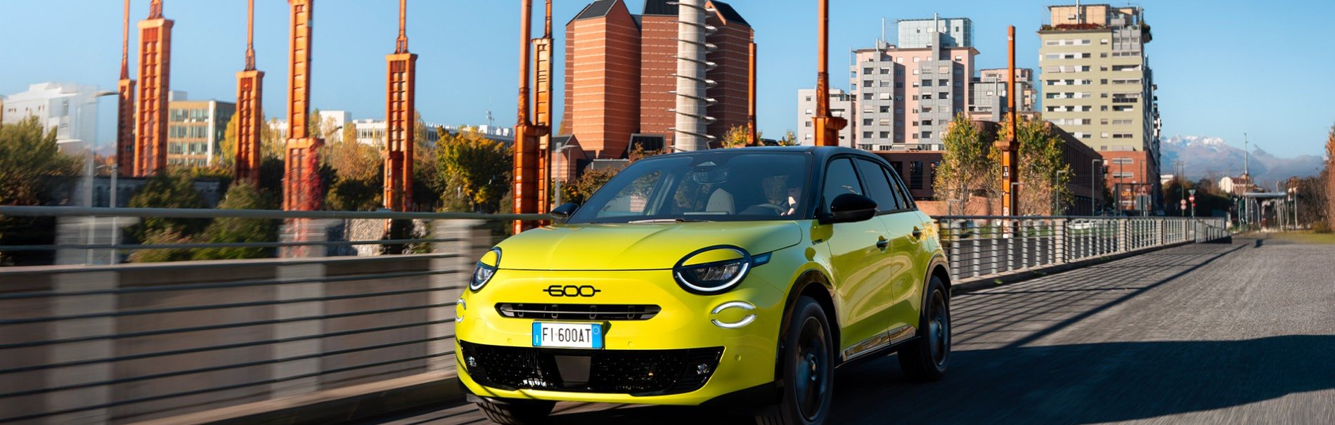 Lime green car driving on a city road with modern buildings in the background.