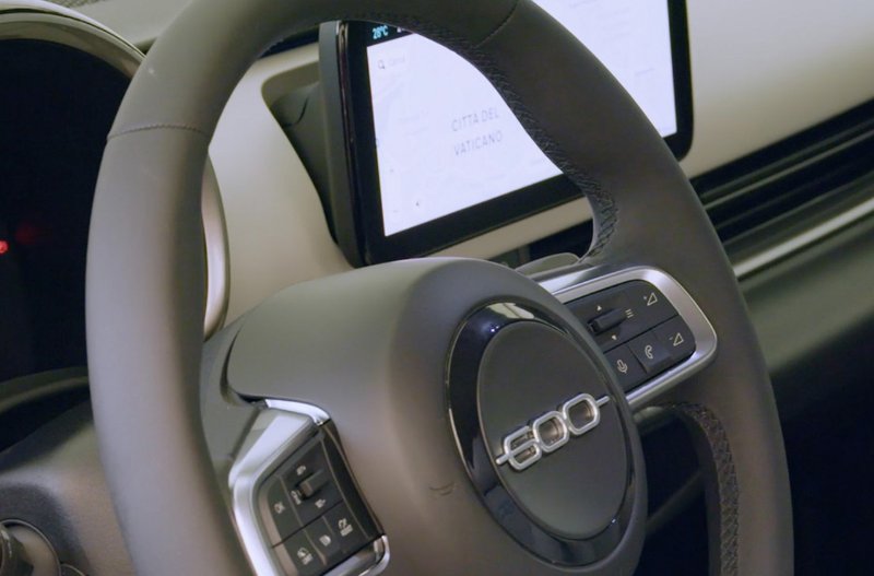 Steering wheel and dashboard touchscreen of a Fiat 500 vehicle interior.