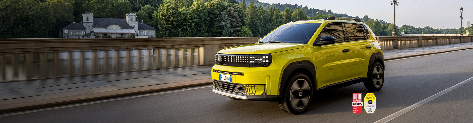 Yellow SUV driving on a road beside a bridge, awards logos visible in the corner.