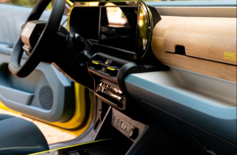 Close-up of a car interior featuring a large screen and bamboo dashboard.