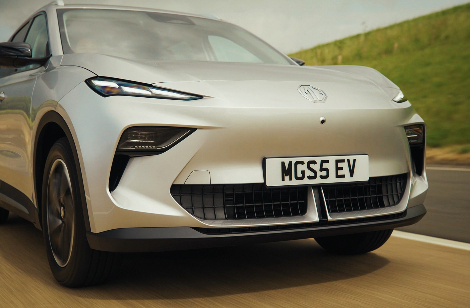 Silver MG5 EV car driving on a road, front view showing number plate MG5S EV.