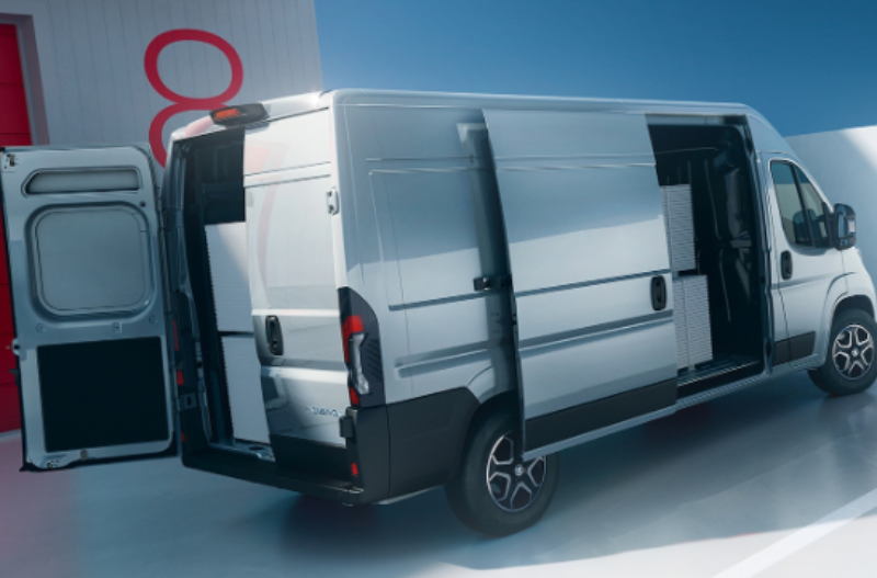 Silver van with open rear and side doors, parked near a red loading dock.
