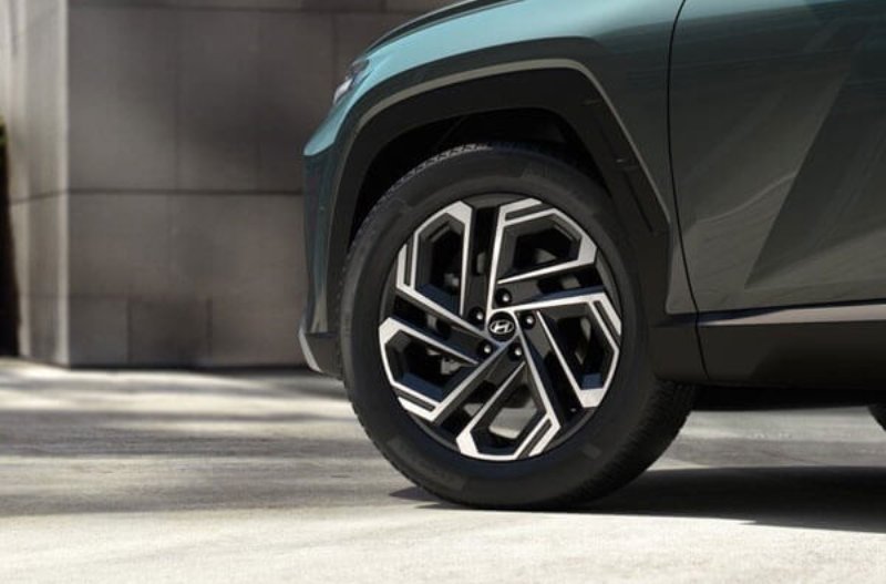Close-up of a car's front wheel and tyre with a geometric alloy wheel design.