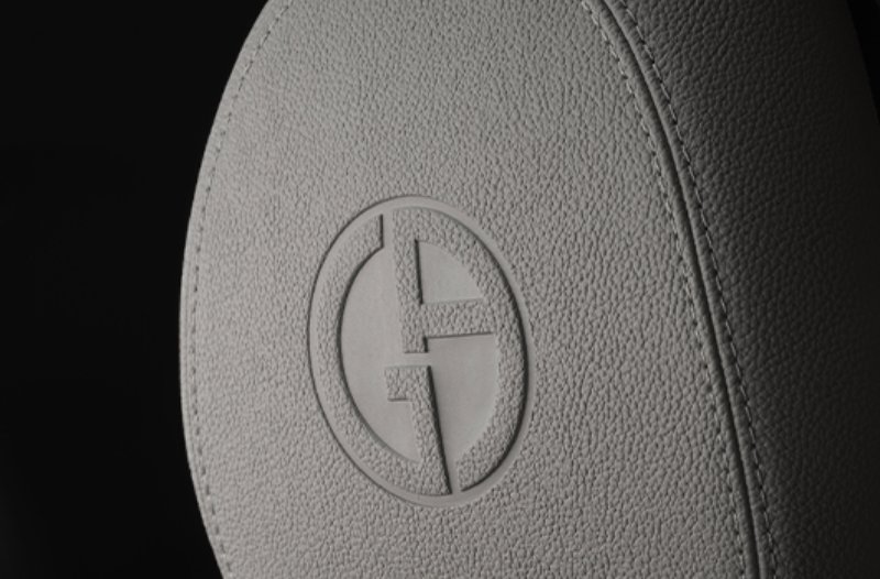Close-up of a car headrest with a logo embossed in grey leather.
