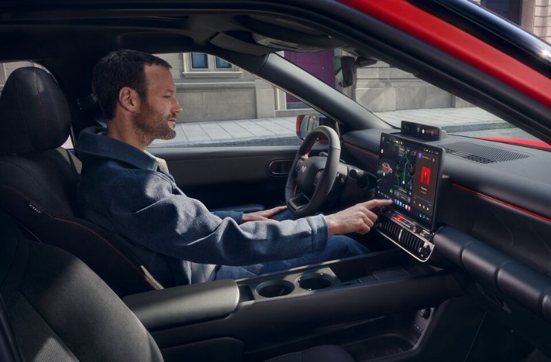 Man using touchscreen controls in a parked car.