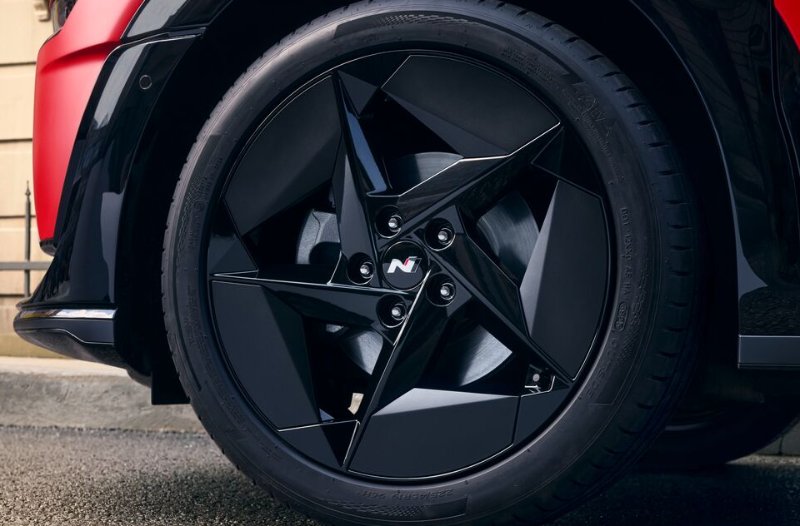 Close-up of a black alloy wheel on a red vehicle.