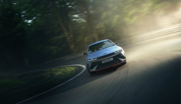 Silver car taking a sharp turn on a misty road.