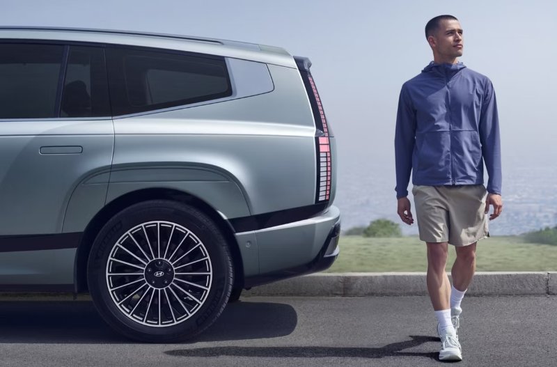 IONIQ 9  side view of wheels and man walking next to the car