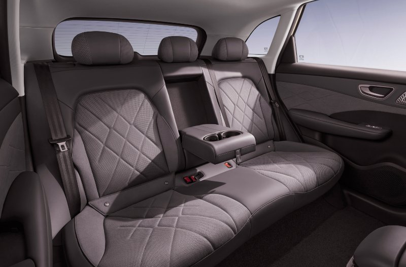 Grey quilted car back seats with a foldable armrest and cup holders.