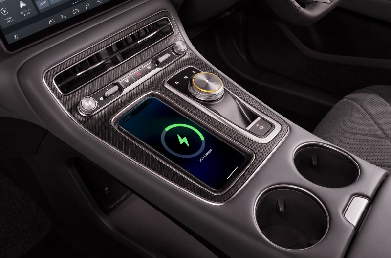 Car interior with smartphone charging wirelessly on centre console.
