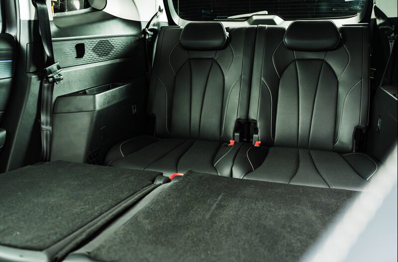 Car interior showing black leather rear seats with folded down seats in the foreground.