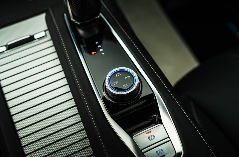 Close-up of a car's central console with gear selector and control dial.
