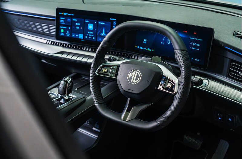 Steering wheel and dashboard display of an MG car interior.