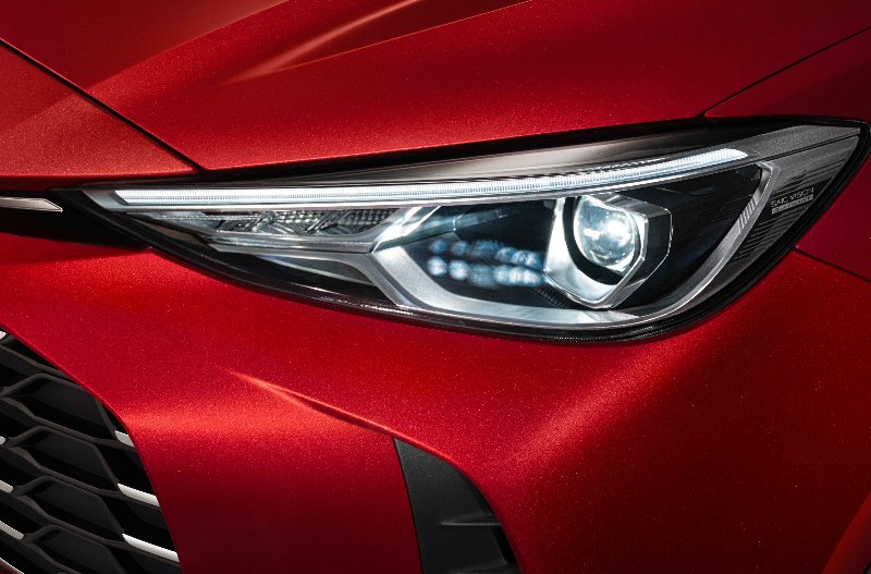 Close-up of a red car's headlight and front grille.