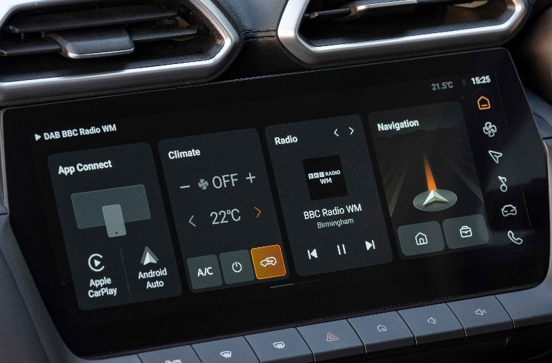 Close-up of a car touchscreen display with radio, climate, and navigation controls.