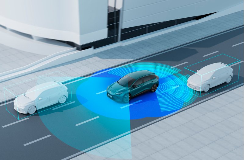 Car demonstrating autonomous driving sensors on a roadway.