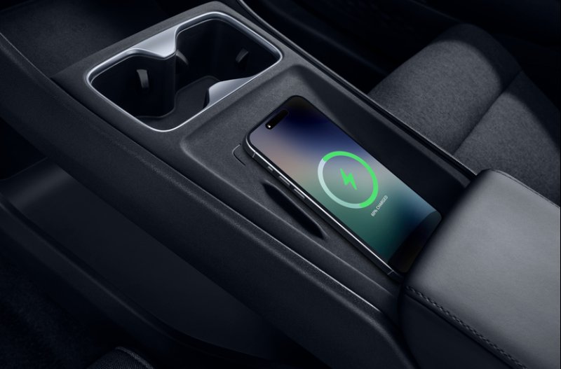 Smartphone wirelessly charging in a car's centre console charging slot.