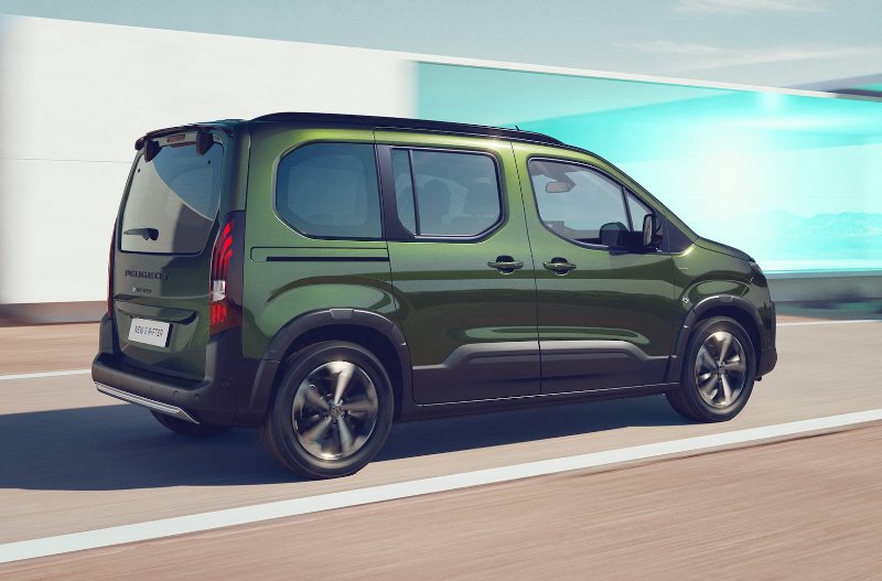 Green Peugeot Rifter driving on a road, side view.