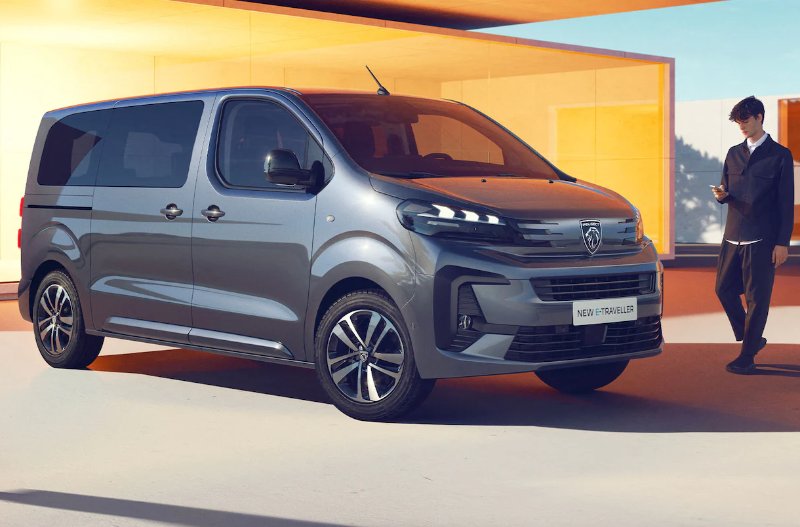 Grey van with futuristic design parked near two people dressed in dark clothing.