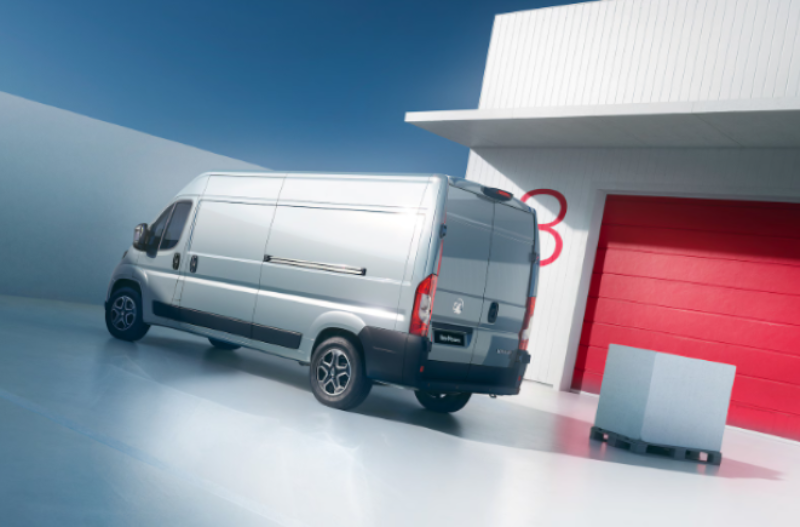 Silver van parked near red garage door with a pallet in front.
