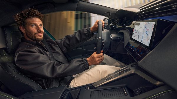 Man driving a car, holding the steering wheel and looking ahead.