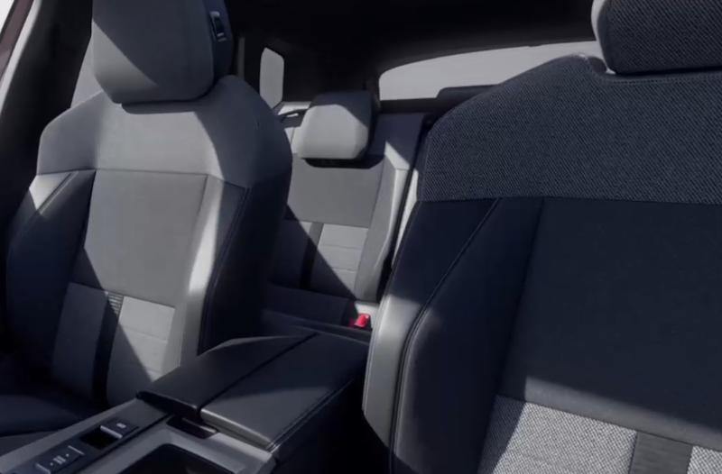 Car interior featuring front and rear black fabric seats with a centre console.