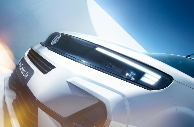 Close-up of a white car's front grille and LED headlights.