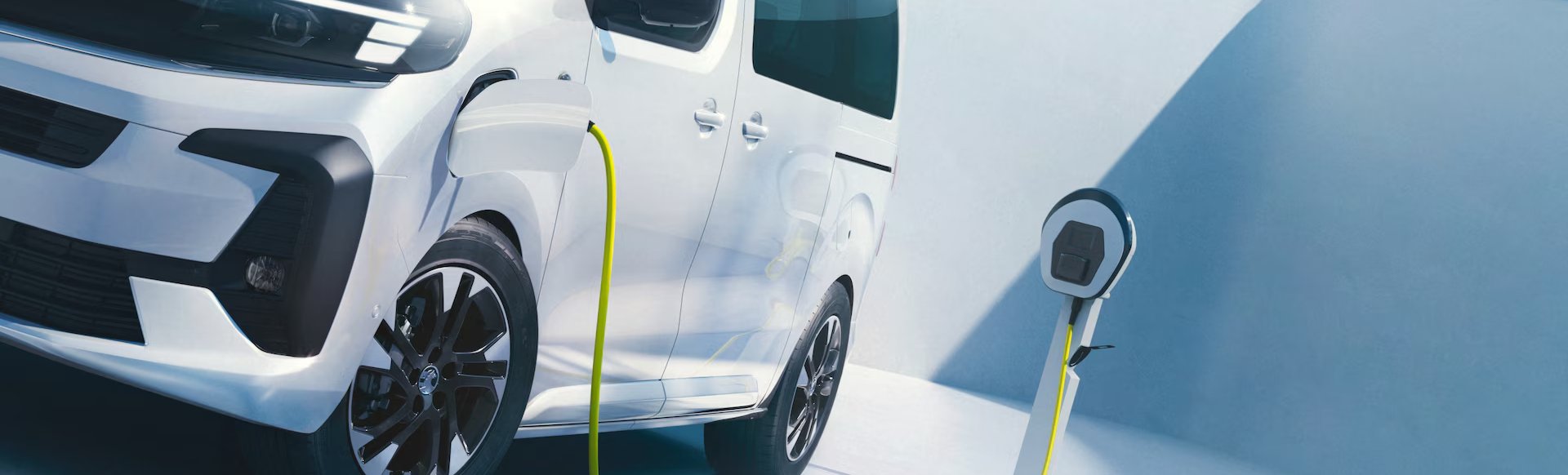 Electric van charging with a yellow cable at a charging station.