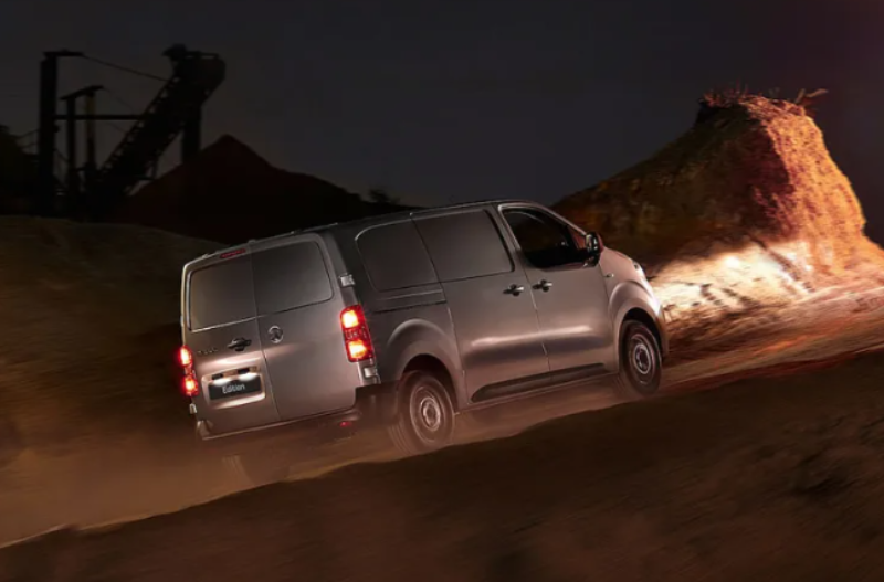 Silver van driving on a dirt road at night.