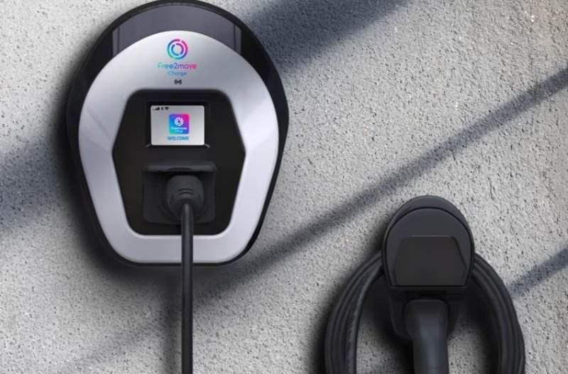 Electric vehicle charging station on a wall with cable coiled on the side.