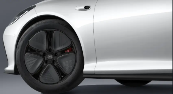 Close-up of a white car's front wheel and tyre with a unique five-spoke design.