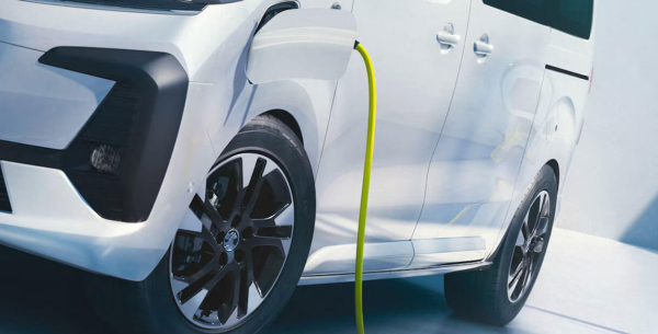 Electric vehicle charging at a station with a yellow cable attached.